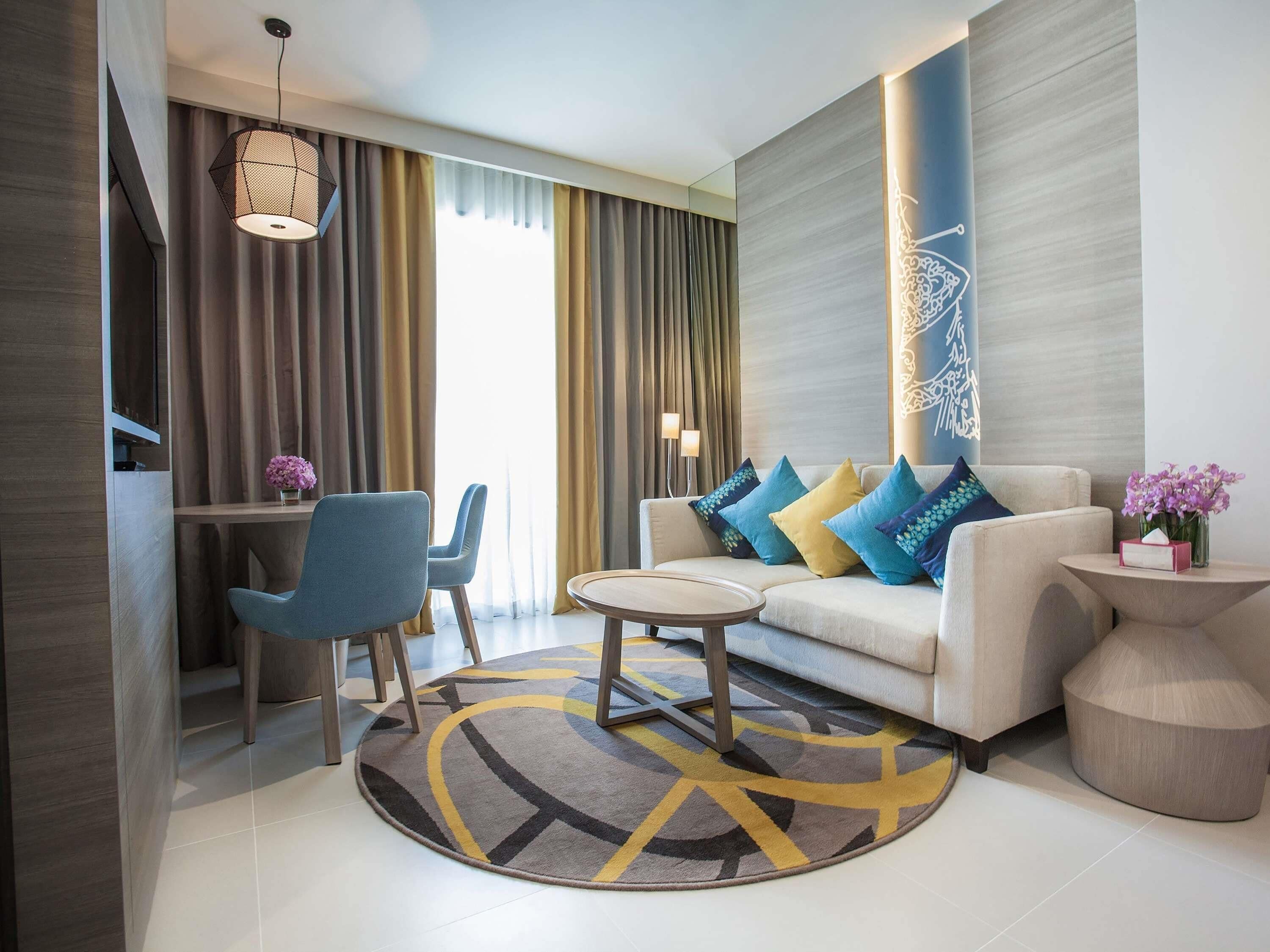 Een moderne woonkamer met een bank, twee fauteuils, een salontafel en een decoratief wandobject.