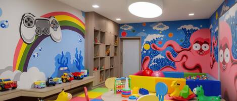 A children's playroom with colorful toys, a play table, and a wall mural.