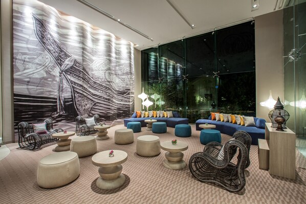 A modern lounge area with a large abstract mural, comfortable seating, and ambient lighting. - Mercure Pattaya Ocean Resort (Pattaya)