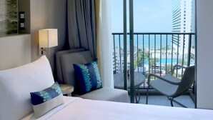 A hotel room with a bed, a chair, a table, and a balcony with a view of a building and a pool. - Mercure Pattaya Ocean Resort (Pattaya)