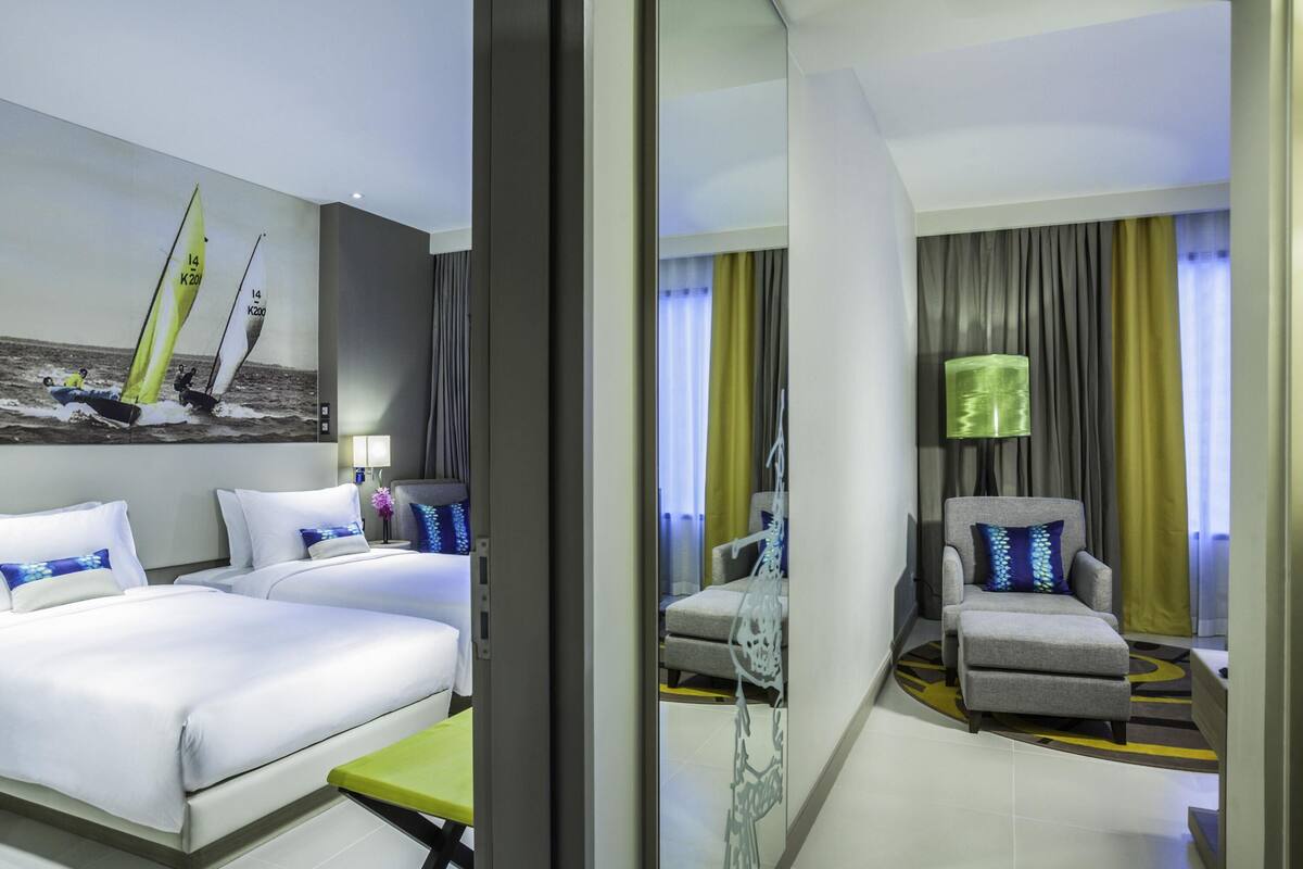 A modern hotel room with a bed, a desk, a chair, and a large window with curtains.