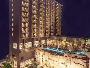 A multi-story hotel with balconies, a pool area, and a waterfall feature.