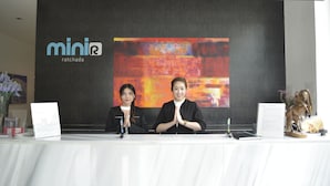 A reception desk with a logo, a large abstract painting, and a small statue.