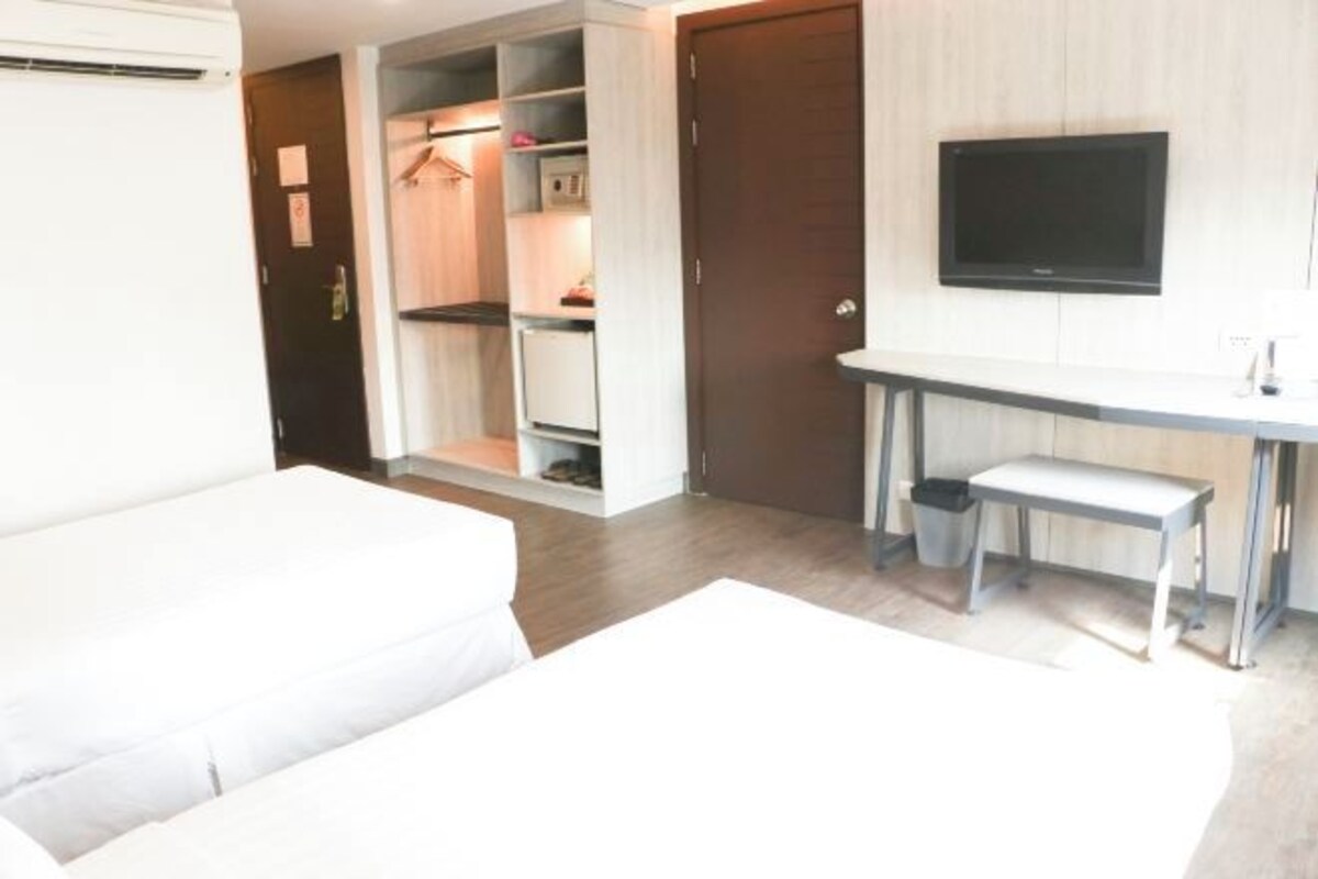 A hotel room with a bed, a desk with a chair, a television, and a wardrobe.
