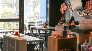 An indoor dining area with tables and chairs, a counter with a menu, and decorative elements on the wall.