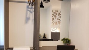 A modern bathroom with a shower, a sink with a mirror, a chair, and a towel rack.