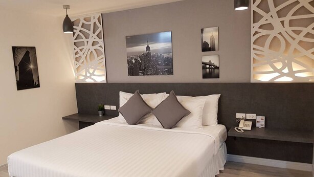 A modern hotel room with a large bed, a cityscape view, and a decorative wall panel.