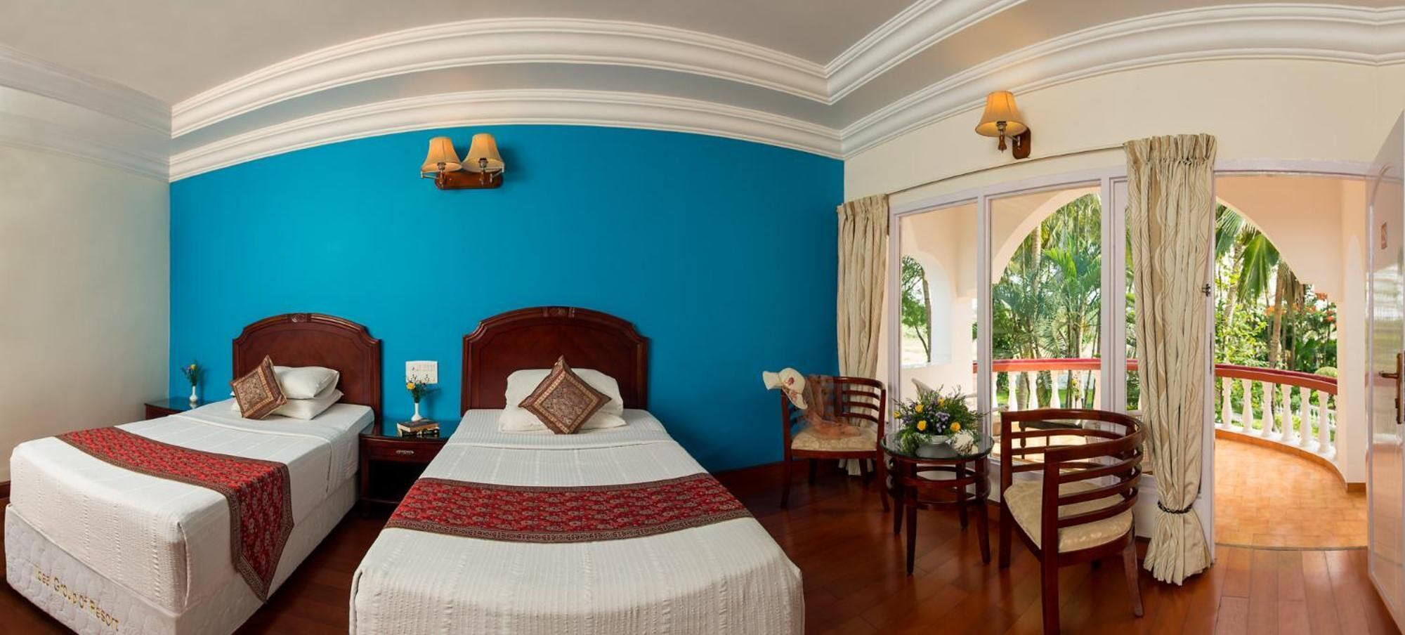 A hotel room with two beds, a balcony with a view, and a dining area with chairs.