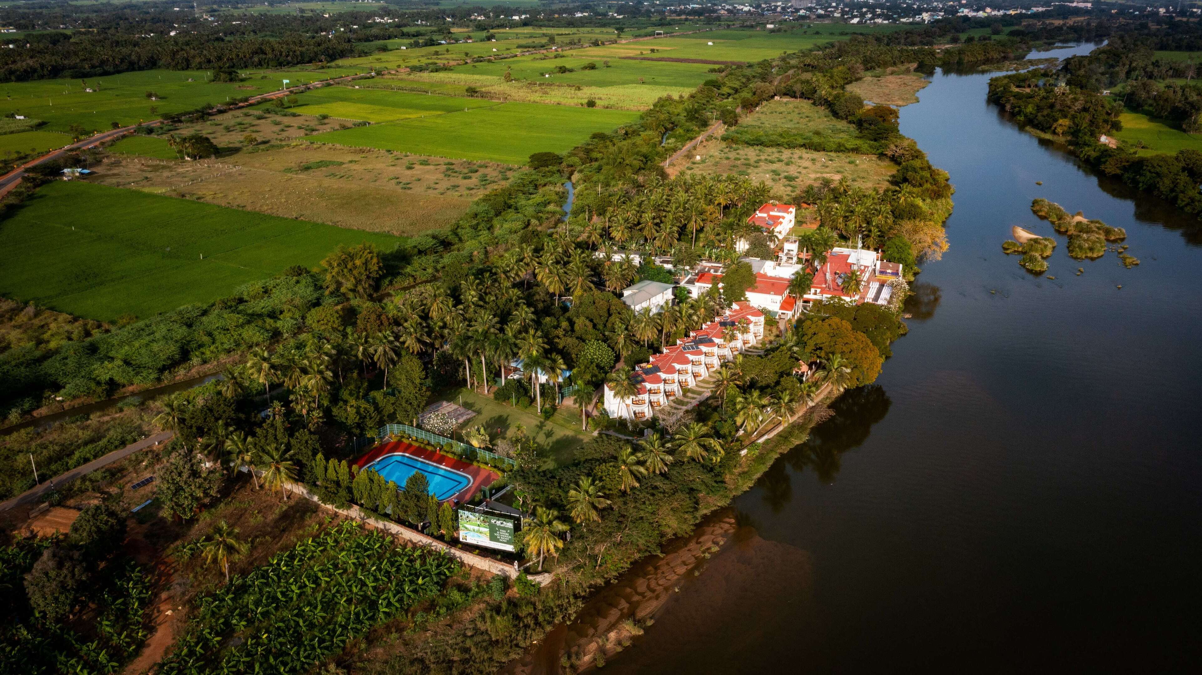 Vista aèria d'un complex turístic amb diversos edificis, una piscina i un riu.