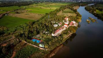 An aerial view of a resort with multiple buildings, a swimming pool, and a river.