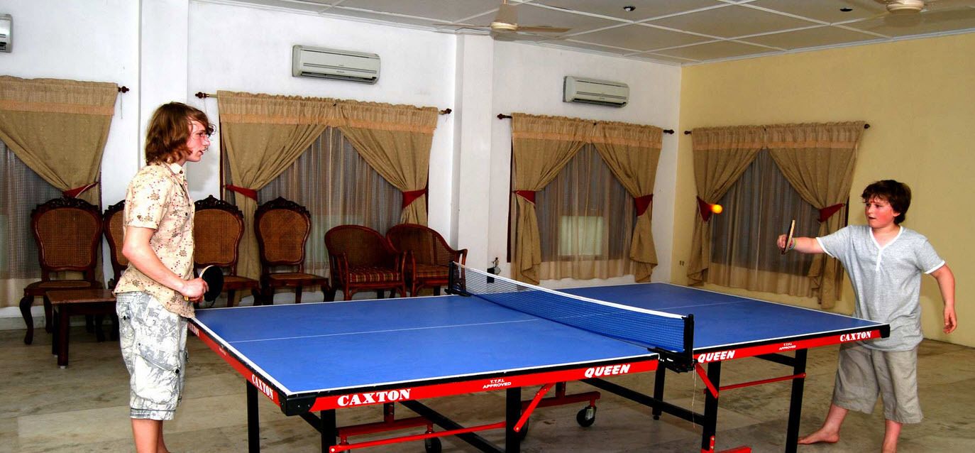 Ein Tischtennis-Tisch in einem Raum mit Stühlen und Vorhängen.
