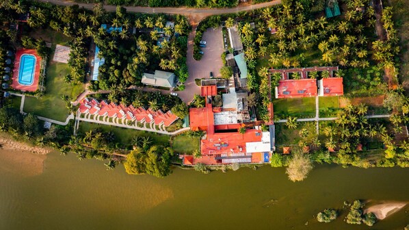 An aerial view of a resort with a swimming pool, tennis courts, and a large building with a red roof. - Great Trails River View Resort Thanjavur by GRT Hotels (Thanjavur)