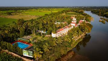 A resort with a swimming pool, surrounded by lush greenery and a river.