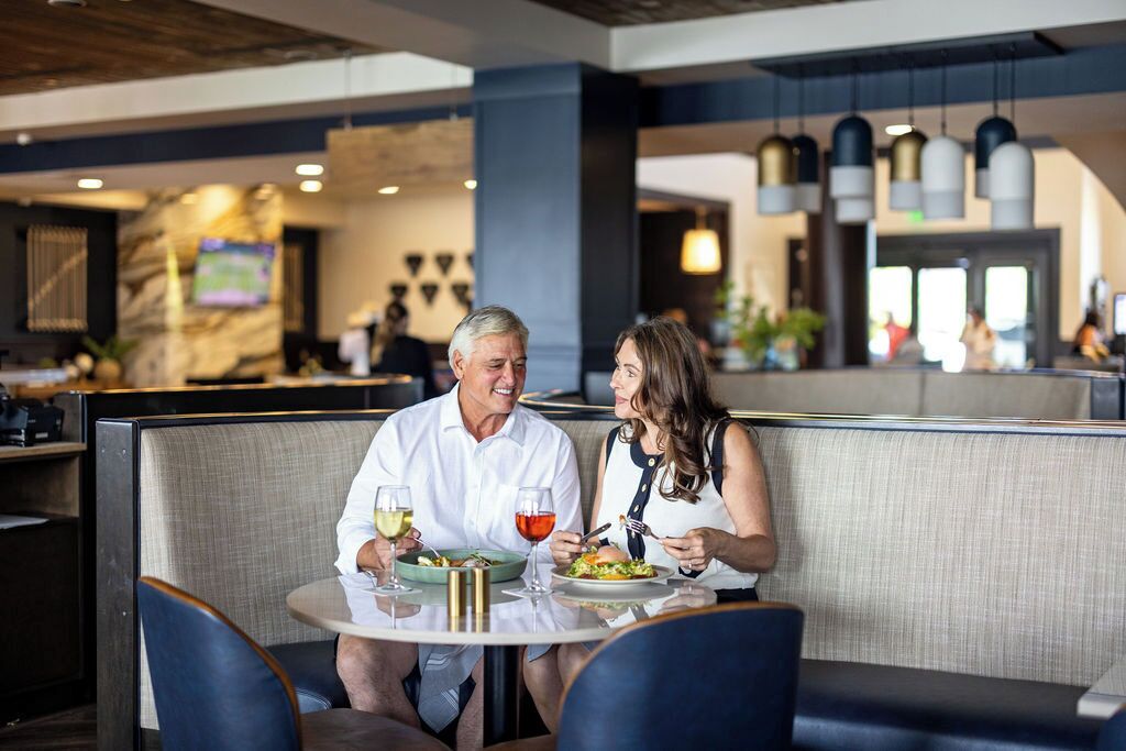 A couple dining in a modern restaurant with a marble wall and pendant lighting.