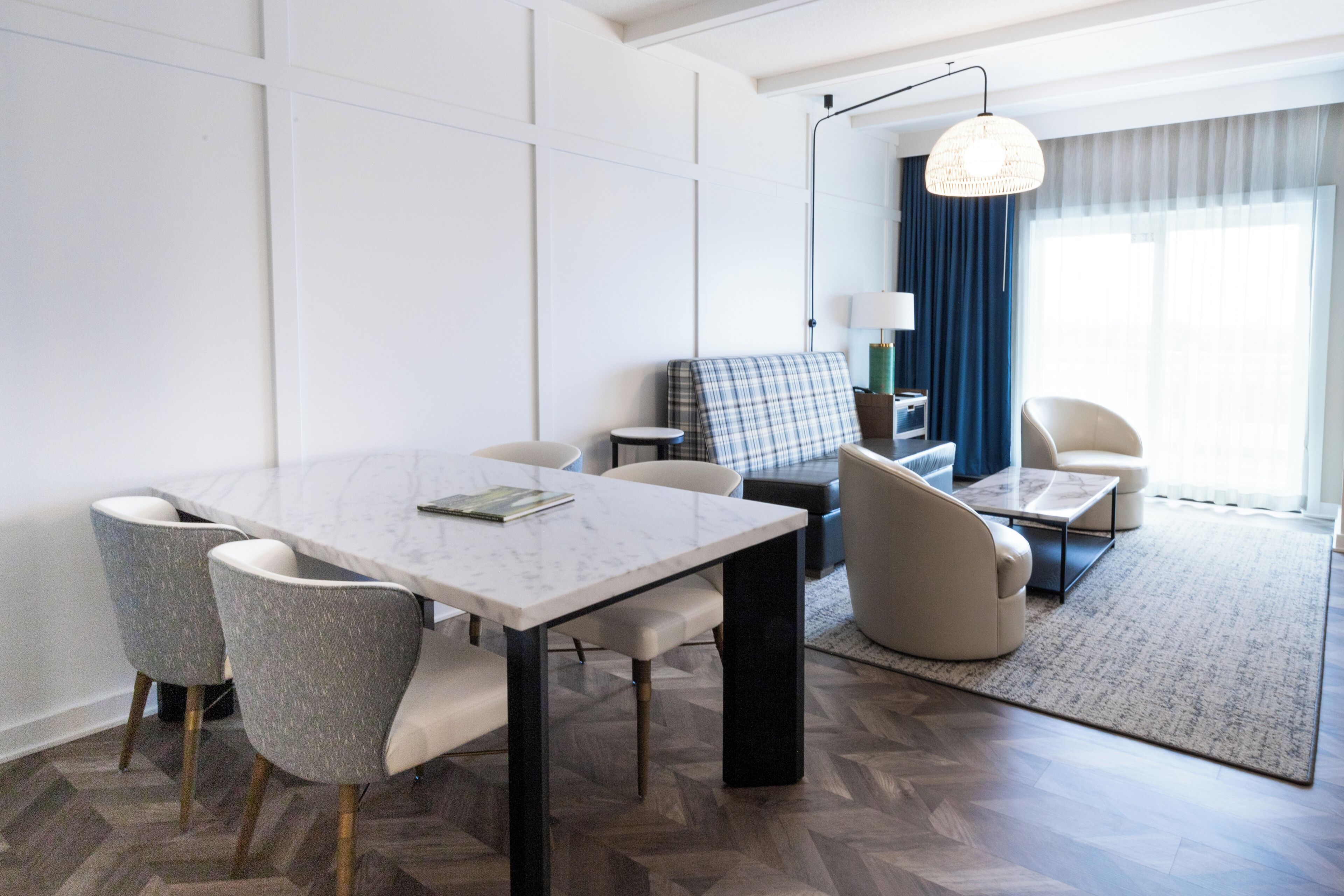 Una camera d'albergo moderna con zona pranzo, divano, tavolino e vista sull'esterno.