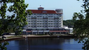 A multi-story hotel with a red roof, located near a body of water with a sailboat. - The Inn At Harbor Shores (Saint Joseph)