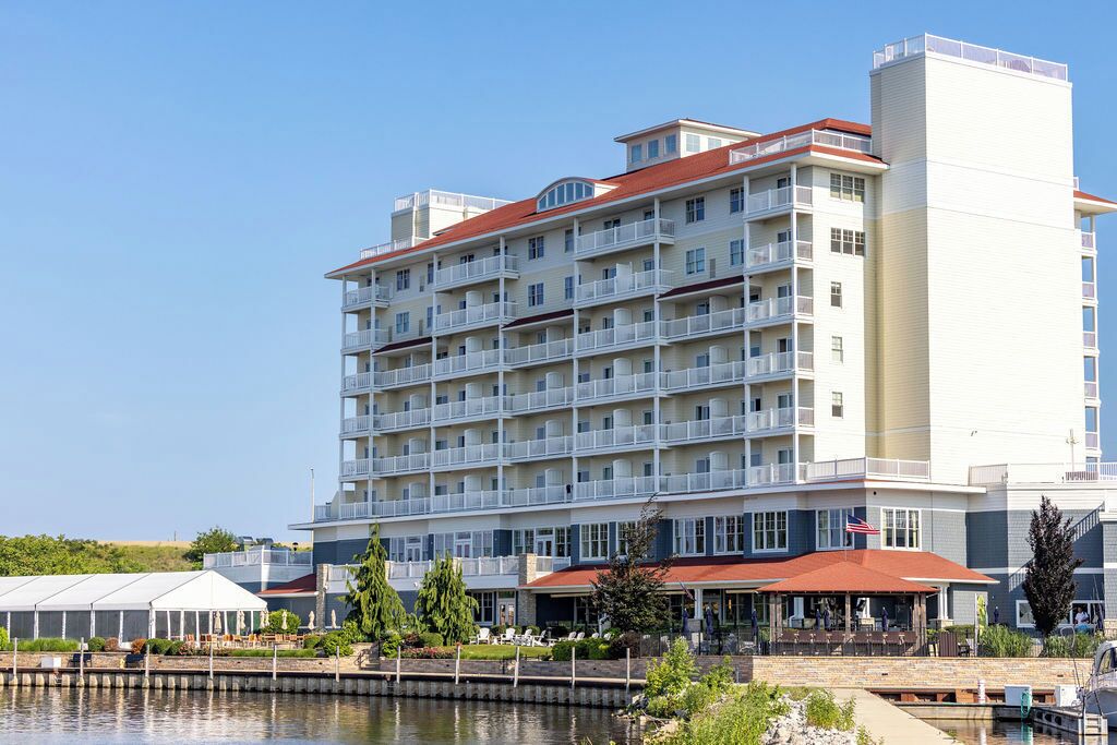 Un hotel de varios pisos con balcones, piscina y un área de estar al aire libre techada.