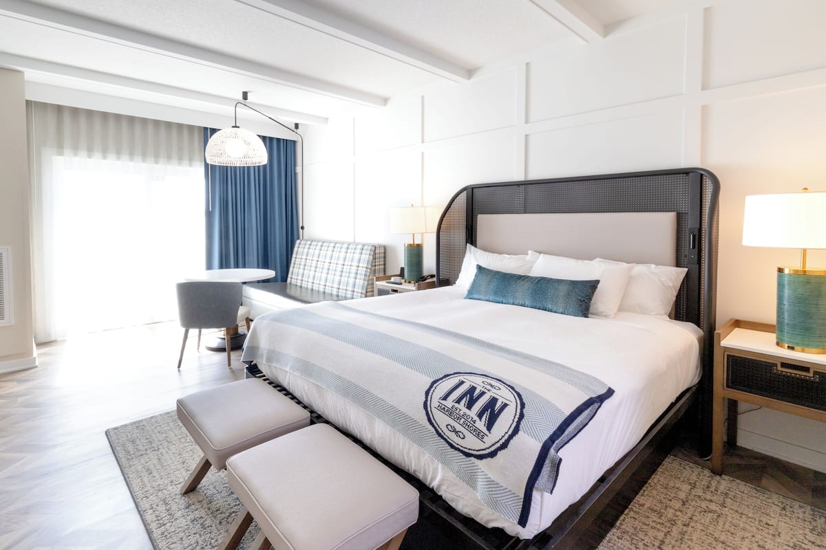 Ein Hotelzimmer mit einem großen Bett, einem Schreibtisch, einem Sessel und einem Fenster mit Vorhängen.