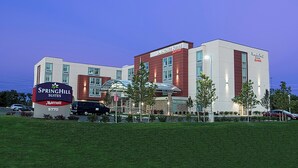 A modern hotel with a prominent sign, multiple entry points, and a parking area.