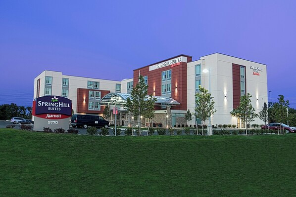 A modern hotel with a prominent sign, multiple entry points, and a parking area.