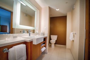 A modern bathroom with dual sinks, a toilet, and a large mirror.