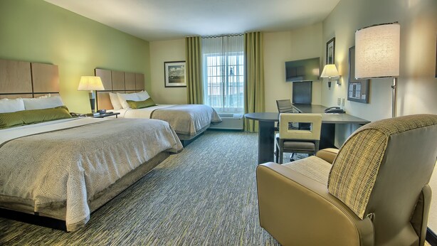 A hotel room with two beds, a desk, a chair, a TV, and a window with curtains. - Candlewood Suites Columbus - Grove City by IHG (Grove City)