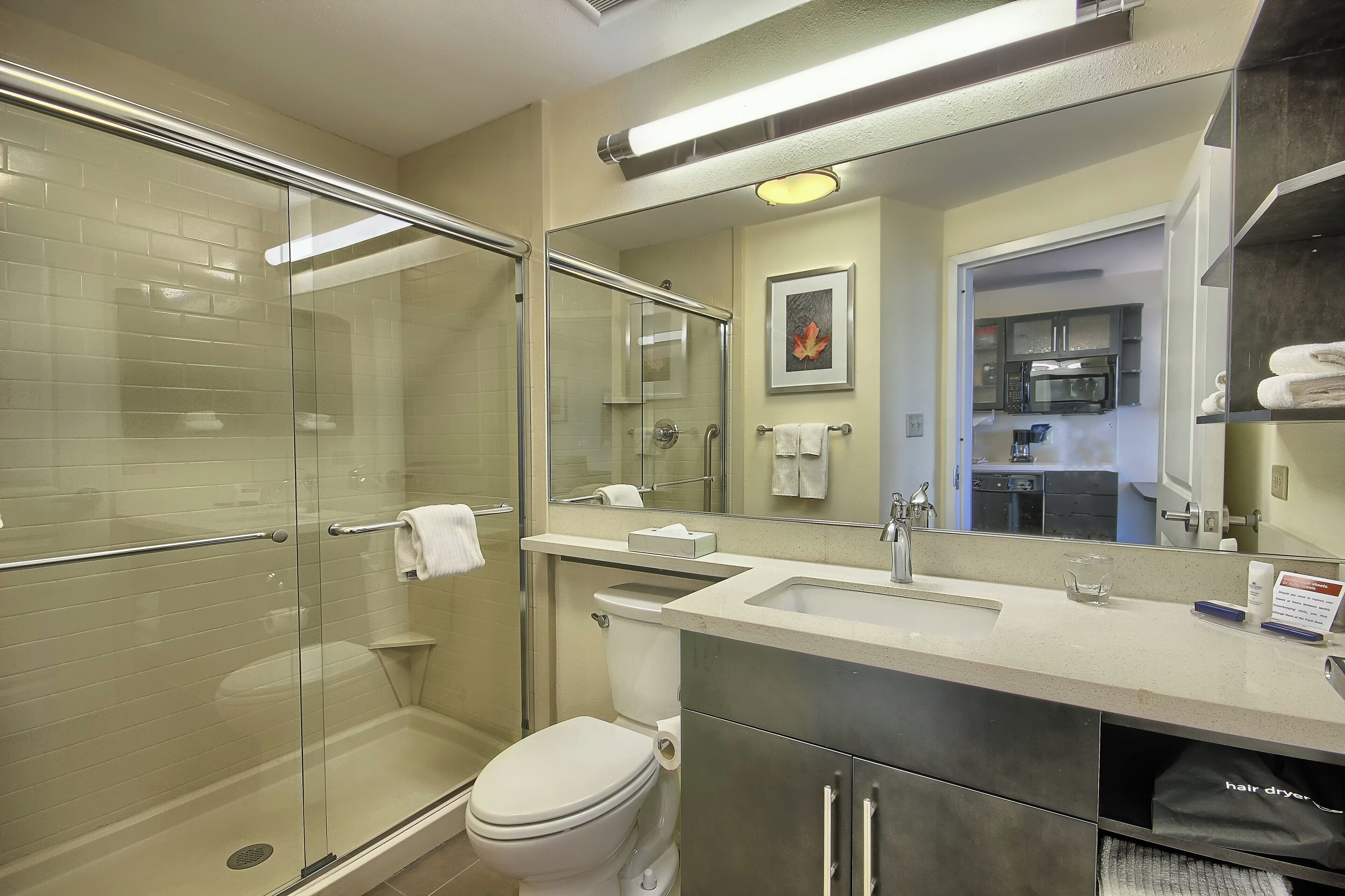 Une salle de bain avec une douche à parois de verre, des toilettes, un lavabo et un miroir.