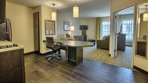 A hotel room with a dining area, a kitchenette, a sofa, and a large window with curtains. - Candlewood Suites Columbus - Grove City by IHG (Grove City)