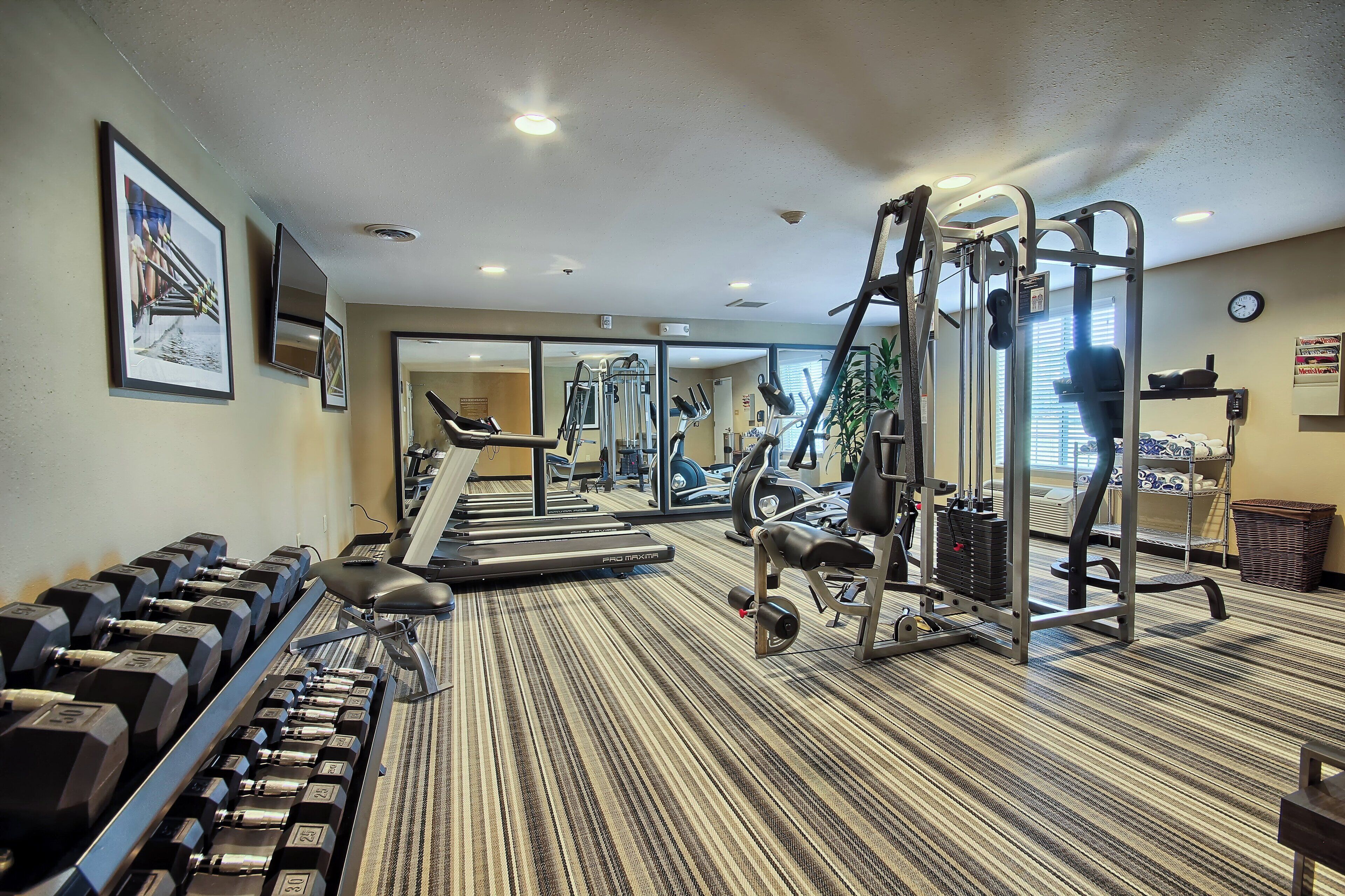 Un gimnasio con cintas de correr, mancuernas y máquinas de pesas.