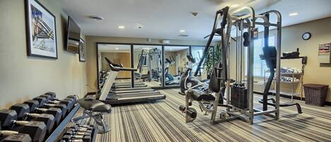 Un gimnasio con cintas de correr, mancuernas y máquinas de pesas.