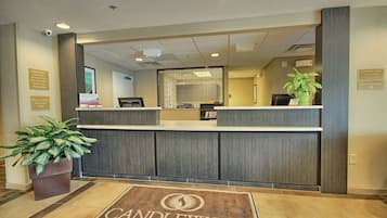 A hotel reception desk with a modern design, a welcome sign, and a plant.