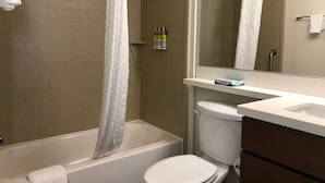 Een badkamer met een bad, toilet en een spiegel.