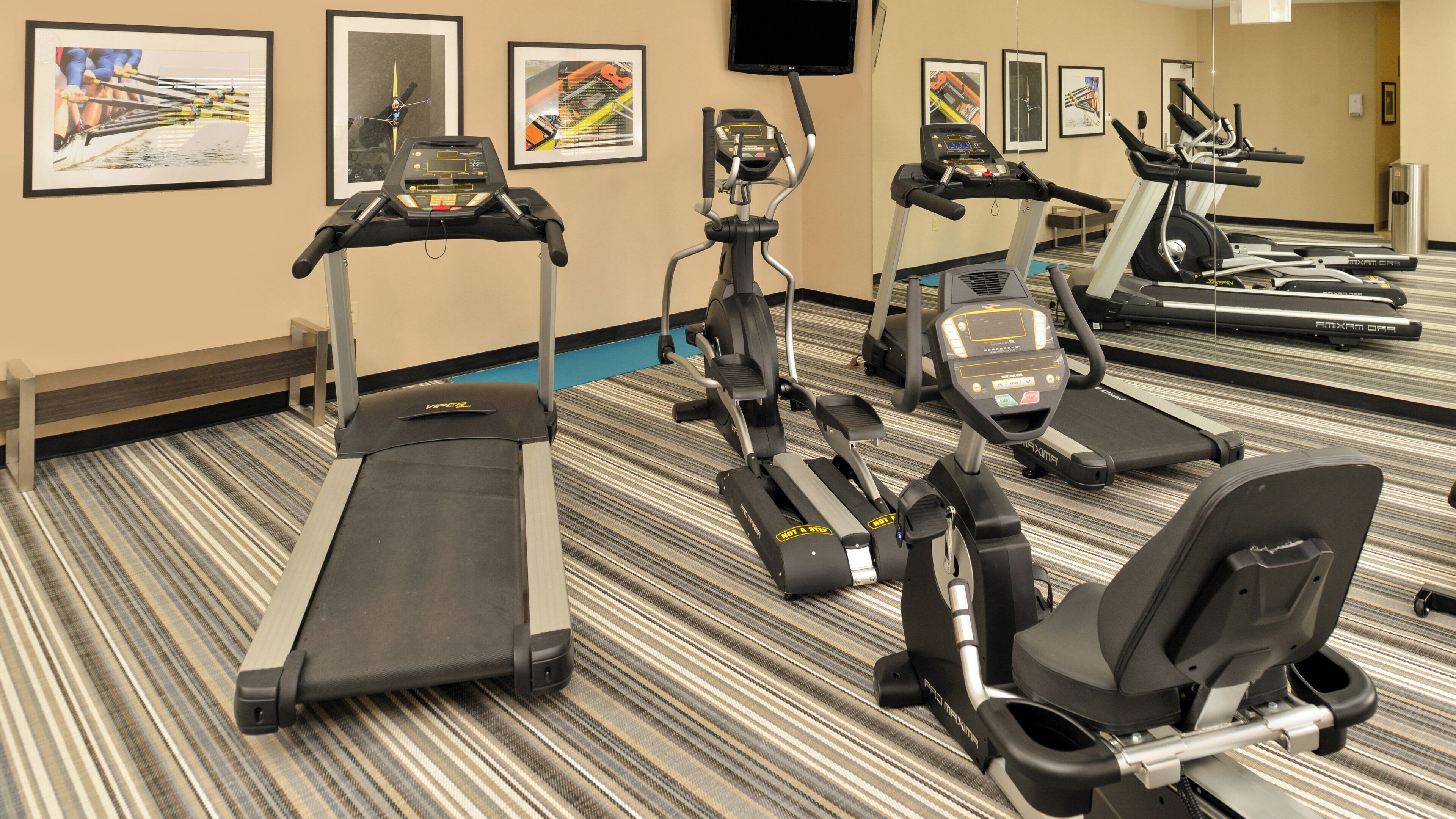 A hotel gym with multiple treadmills, ellipticals, and stationary bikes.
