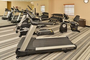 Un gimnasio con cintas de correr Pro Maxima, mancuernas y bicicletas estáticas.