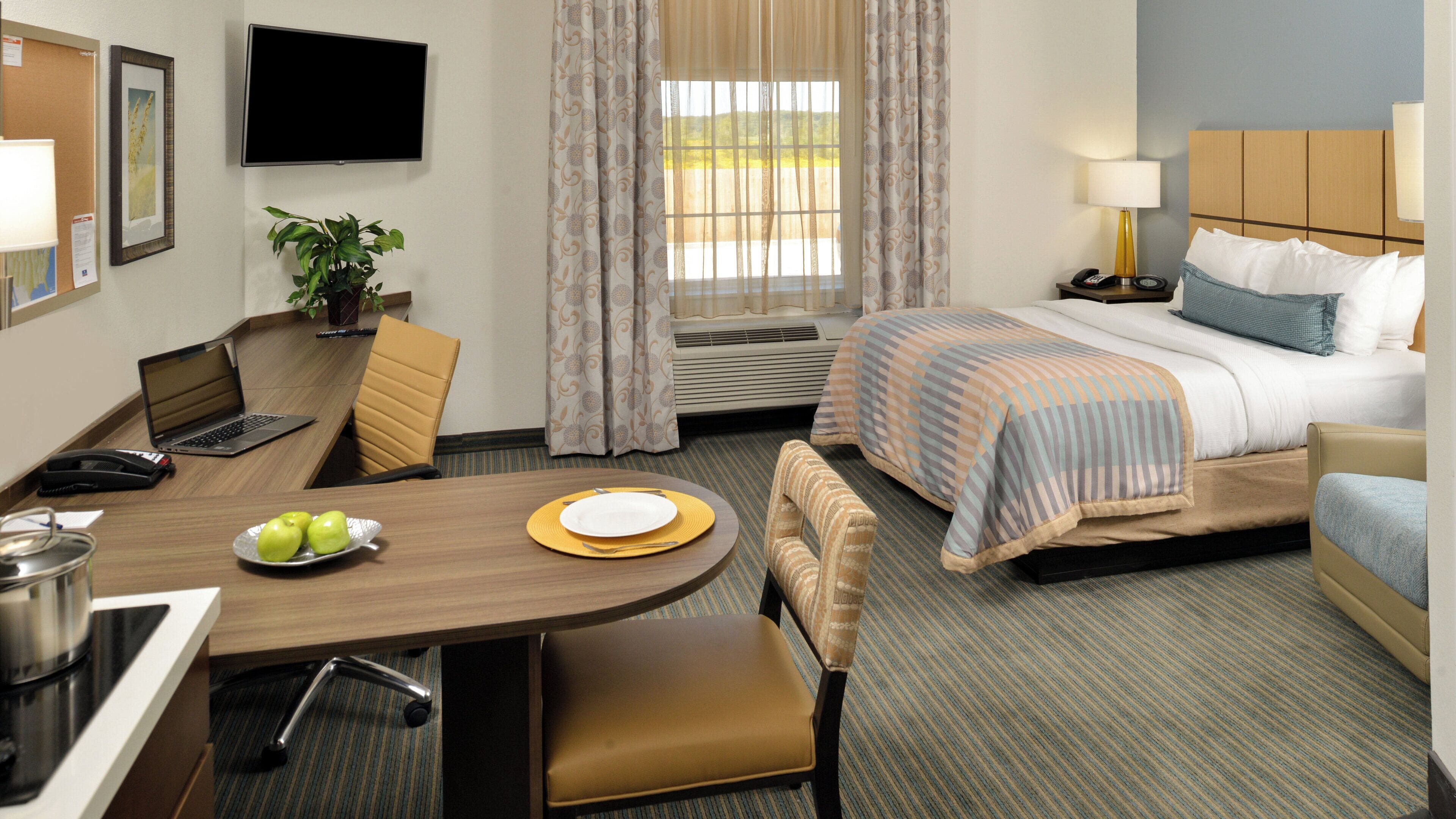 Una habitación de hotel con cama, escritorio, silla, mesa de comedor y televisor.