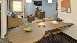 Een moderne hotelkamer met een zithoek, een bank, een televisie en een kleine plant.