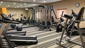 A gym with various exercise equipment, including treadmills, elliptical machines, and free weights.