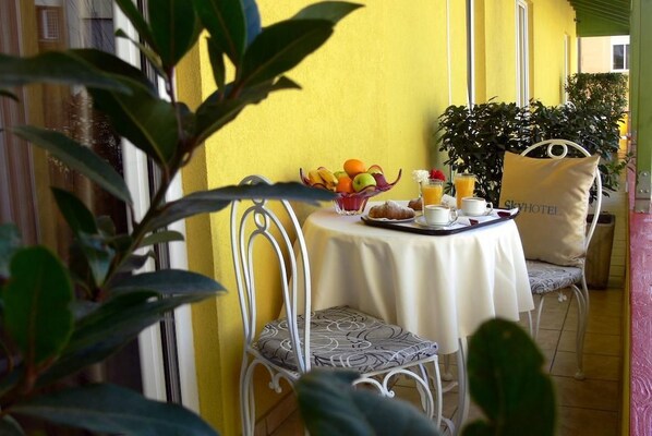 A table set with breakfast items, a chair, and a plant in a yellow room. - Sky 2 (Tirana)
