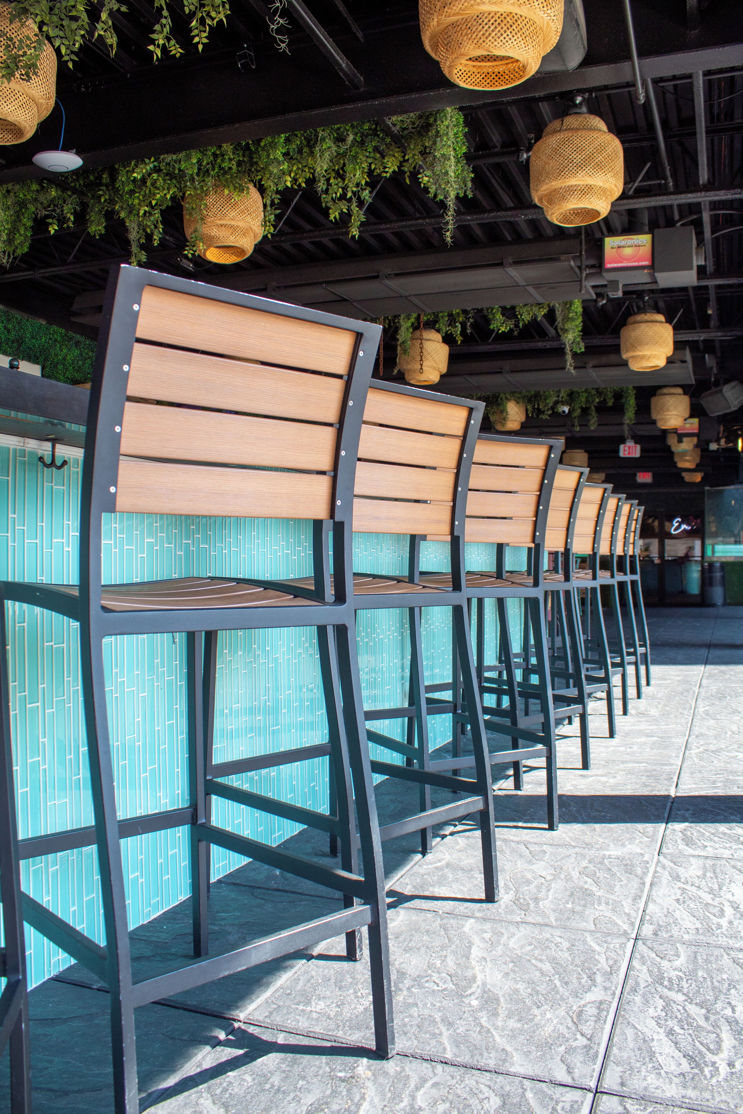 Rows of wooden chairs with metal frames, arranged in a line on a tiled floor.