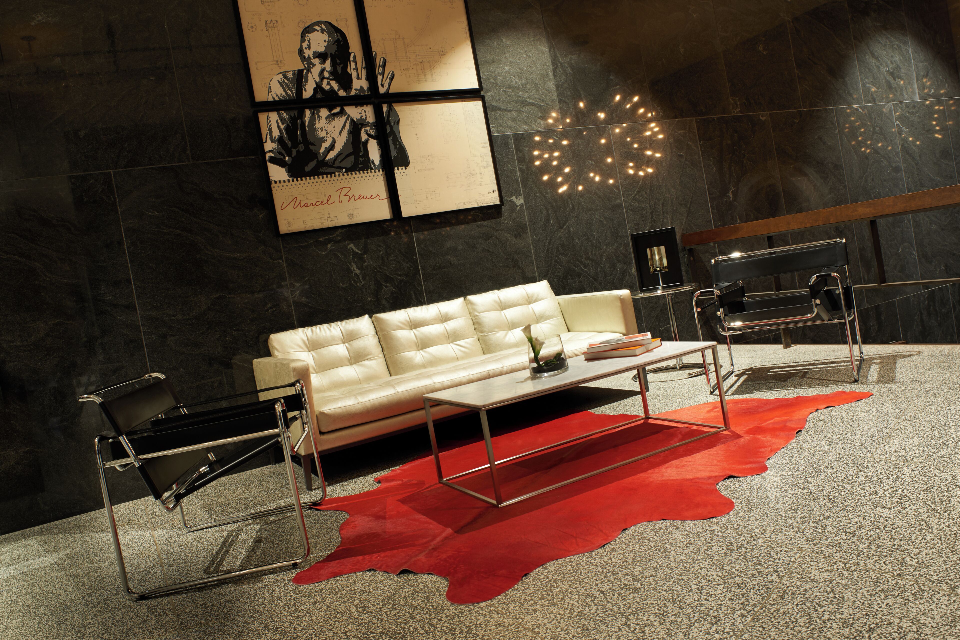 A modern living room with a white sofa, a red rug, and a minimalist coffee table.