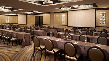 A conference room with multiple tables, chairs, and a large screen.