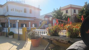 Ein Hotel namens 'el lago' mit Restaurant im Erdgeschoss, Außenbereich und Topfpflanzen.