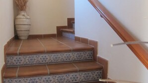 Eine Treppe mit braunen und blauen Mustertapeten, einem hölzernen Geländer und einem runden Spiegel an der Wand.