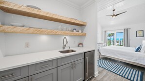 A modern kitchen with wooden shelves, a sink, and a built-in refrigerator. - Inn on the Beach - 18+ only (St. Pete Beach)