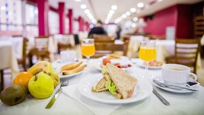 A breakfast setting with a sandwich, fruits, and beverages on a table. - Hotel Biarritz (Gandia)