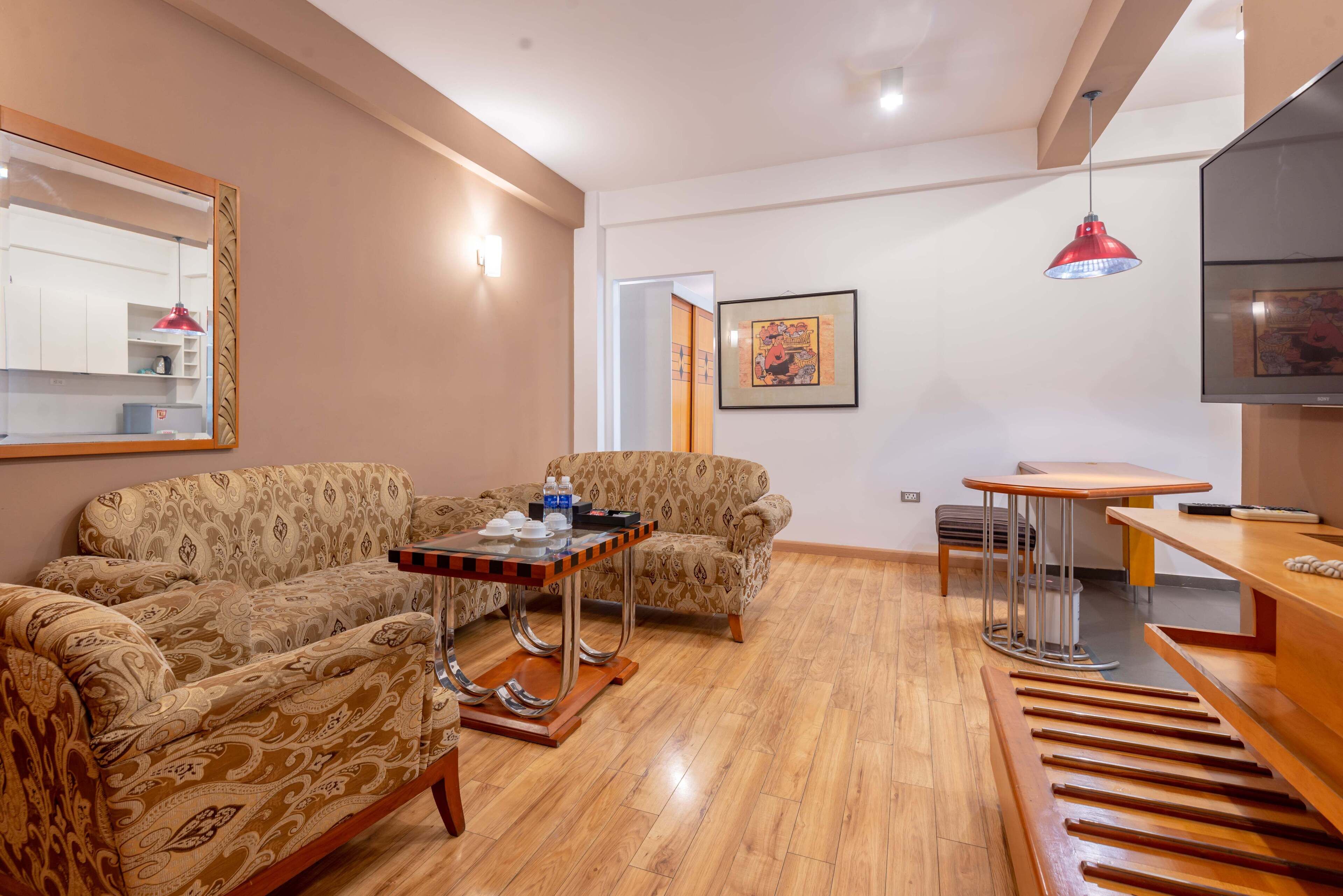 Una sala de estar con sofás estampados, una mesa de centro, un televisor y un comedor.