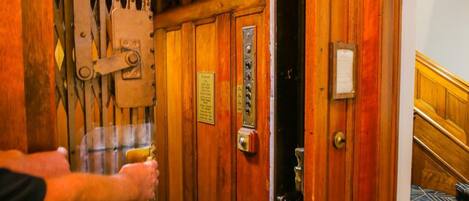 A wooden door with a brass handle and a keyhole, leading to a room with a patterned carpet.