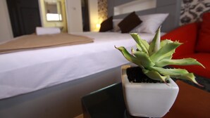A hotel room with a bed, a small potted plant, and a red couch. - Bearing 26 Hotel (Samut Prakan)