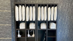 A storage unit with neatly folded white towels and neatly stacked folded towels. - GR Hotel Ginzadori (Kumamoto)