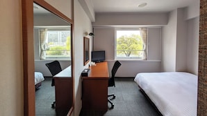 A hotel room with a bed, a desk with a computer, a chair, a mirror, and two windows with curtains. - GR Hotel Ginzadori (Kumamoto)